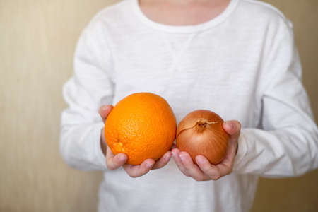 in the hands of the boy vitamins. orange and onion. fight against coronavirus. dose of vitamins. Prevention of post-fever. Healthy food. Vitamin Cの写真素材