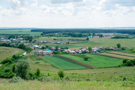 rural landscape with green field and blue sky. summer landscape. top view of the village. river near the field. forest, field, riverの写真素材