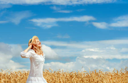 girl in a wheat field. girl looks at the sky. freedom and tranquility. heavenly landscape. the girl loves nature. love for summer. summer landscape. wonderful futureの写真素材