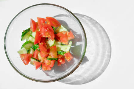 salad with vegetables. summer salad on the table. harvest on a plate. tomato and cucumber are cut into pieces. beautiful reflectionの写真素材