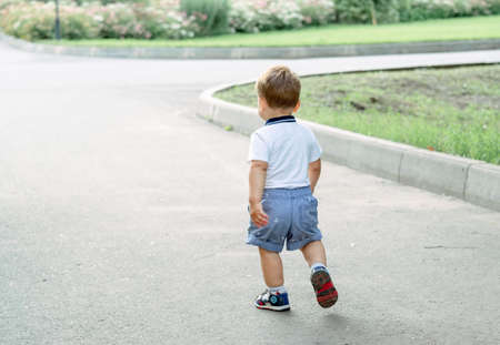 little boy walking along the road. baby's first steps. child steps forwardの写真素材