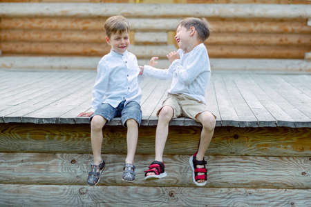 children are sitting on the bench. 2 brothers are fooling around. friends are playing. children laughの写真素材