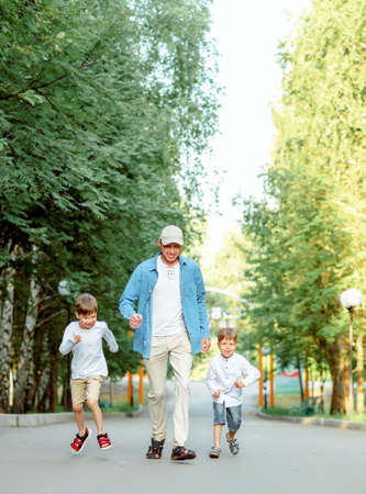 family walking in park. dad and sons are running. Happy dad with children. Dad and 2 sons.の写真素材