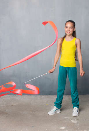 gymnast with ribbon. the gymnast raises her leg high. Good stretch. Sportswoman in a tracksuit. Gymnast pulls a sockの写真素材