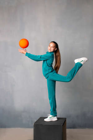 The gymnast raises her leg high. Good stretch. Sportswoman in a tracksuit. Gymnast pulls a sock. gymnast with a ballの写真素材