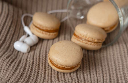 white headphones and caramel macaroons on a sweater. cozy autumn photography. photograph of food in brown tones. winter playlistの写真素材