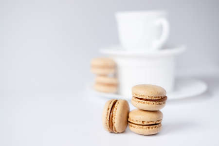 macarons in a coffee cup. caramel macaroons. Light flatley with dessert. Macaroni on white background. Cozy winter photographyの写真素材