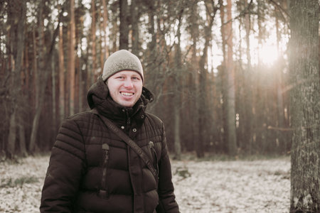 Smiling man in the winter forest. Happy man walks in the snowy forest. A guy in a good mood. Hike...