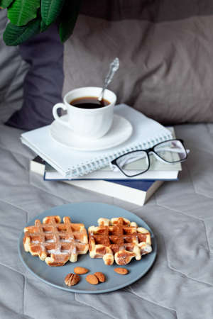 Viennese waffles and coffee in bed. Morning breakfast. Waffles with almond flour. A healthy snack. Still life on a gray bedの写真素材