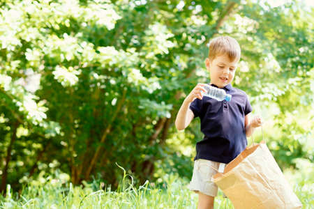 Save environment concept, a little boy collecting garbage and plastic bottles on the beach to dumped...