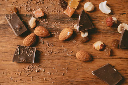 nuts and pieces of chocolate on wooden background. delicious chocolate bars with almond and hazelnuts on a brown background. Sweet foodの写真素材