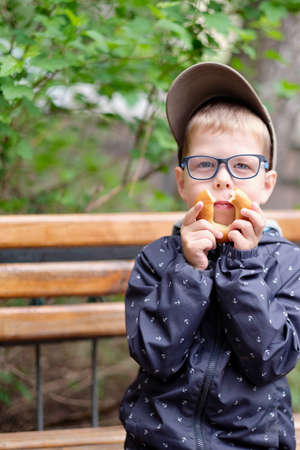 Funny boy with glasses and a bagel. Hilarious photo of a child wearing glasses. A boy with poor eyesight. A child poses and fools around for the camera. Beautiful little boy with glasses making a faceの写真素材