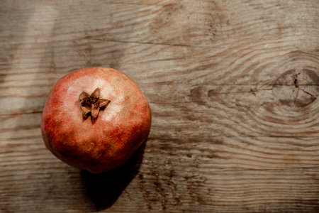 Whole pomegranate over old dark wooden table, top view with space for text. Useful fruit for raising hemoglobinの写真素材