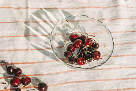 Ripe sweet cherries in a bowl and scattered on a white wooden table. View from above. Washed cherries. Healthy berries in summer. Berry harvestの写真素材