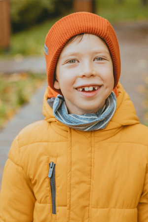 happy boy with a smile in a red cap on the street. Portrait of a smiling boy with big teeth. Portrait of a little boy with a beautiful smile and big eyes.の写真素材