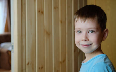 portrait of a smiling boy, on a wooden background, copy space. Cute boy of European appearance, with a dimple on his cheeksの写真素材