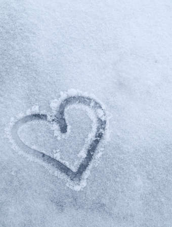 drawn heart on white snow in winter. Vertical photo with a heart drawn in the snowの写真素材