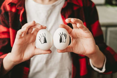 funny picture of a boy with eggs instead of eyes. Eggs with painted eyes. Preparing for Easter. Fun cooking with kidsの写真素材