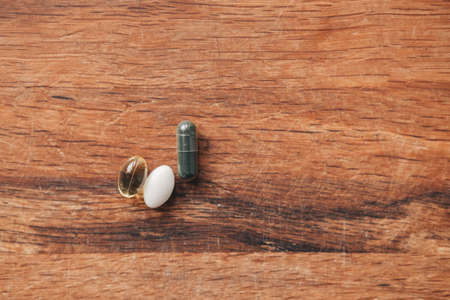 spirulina, fish oil and magnesium in capsules on a wooden background. Vitamins for every day.