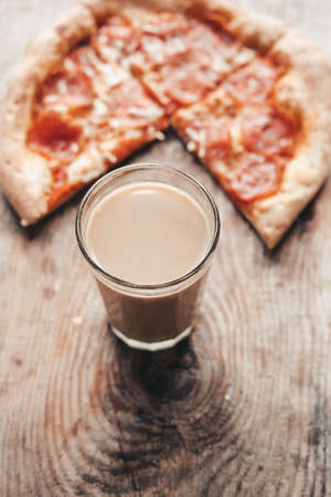 coffee drink in a transparent glass with pizza on a wooden background. Cocoa and pizza, top view.の写真素材