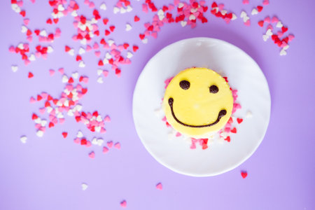 yellow cake emoji with small hearts on a purple background. Valentine's day and birthday conceptの写真素材