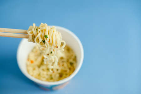 instant noodles with wooden chopsticks on a blue background, top view. Korean national dish.