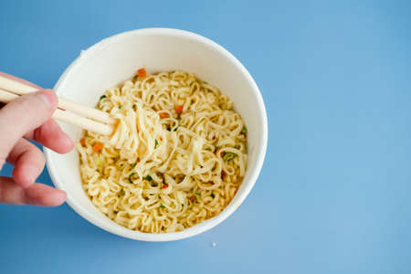 instant noodles with wooden chopsticks on a blue background, top view. Korean national dish.
