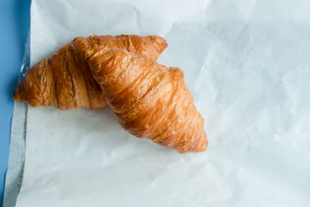 two croissants on paper, on a blue backgroundの写真素材