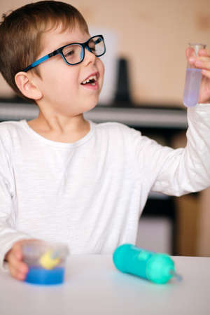 boy is engaged in scientific research. A child with a test tube and a pipette in his hands. The boy...