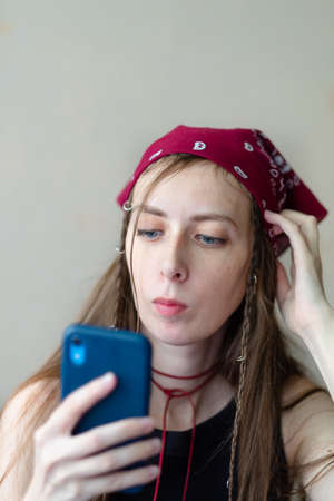 Close-up photo of a beautiful girl in a bandana with a phone in her hands, a news readerの写真素材