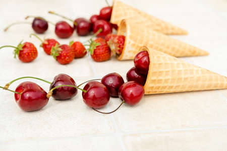 Fresh red cherries in a waffle cone. Ice cream cone with ripe cherries on a white background...