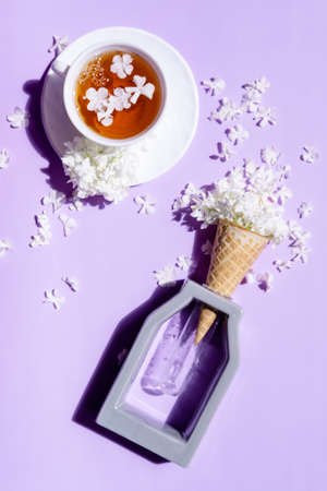 Wafer cone with hydrangea on a purple background. Delicate still life with flowers and a cup of tea. flower ice cream. Trendy color Veri Peri.の写真素材