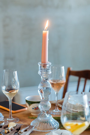 pink candle in a candelabra on a table close-up with glasses of wine and champagneの写真素材