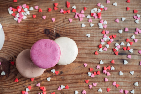 Assorted Macaroon sprinkled with small hearts on a wooden background, top viewの写真素材