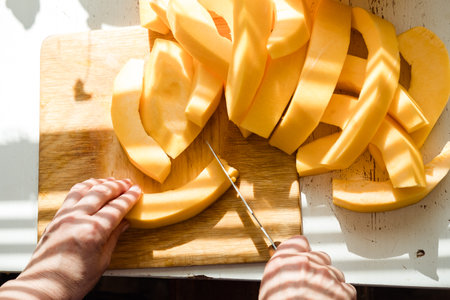 woman's hands with a knife cutting a pumpkin into pieces top viewの写真素材