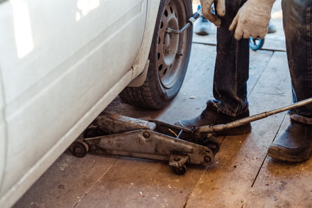 An old jack raises a wheel close-up,in a workshop for carsの写真素材