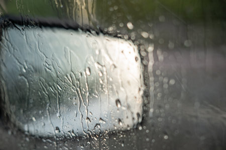Raindrops on the car window and rearview mirror. driving in the rain. sad vibeの写真素材