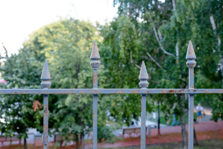 iron tips on the fence against the background of greenery in the parkの写真素材
