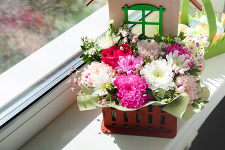 Beautiful bouquet of flowers in basket on the windowsill.の写真素材
