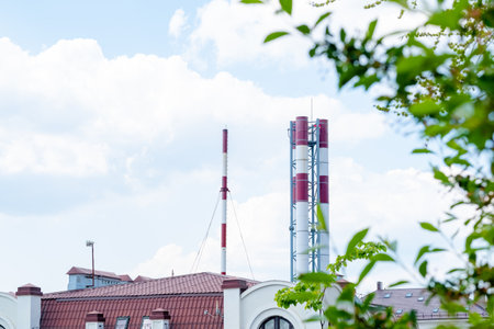 exhaust fumes from a chimney in the city center against a blue skyの写真素材