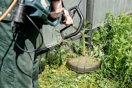 man mows lawn grass with a lawn mower. petrol lawn mower, trimmer close-up. man working in the...