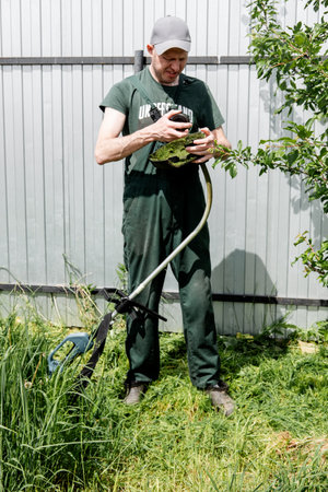 man cleaning the lawn mower from the grassの写真素材