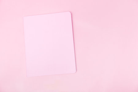 Top view photo workplace with a pink notebook, on an isolated pink background, copy space. female business conceptの写真素材