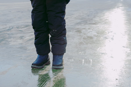 boy skates on ice. The frozen lake. Winter landscape from frozen ice. The boy walks on frozen ice.の写真素材