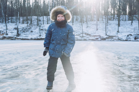 winter holidays in nature. boy walks on ice. Frozen lake on the background of the forest. Traveling with children to the north. child walking in winter.の写真素材