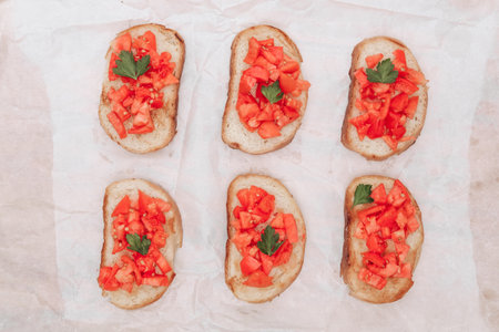 Delicious bruschetta, toasted bread with tomatoes on white paper, top viewの写真素材