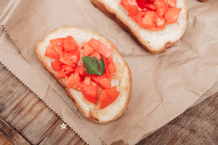 Delicious bruschetta, toasted bread with tomatoes on craft paper, on a wooden backgroundの写真素材