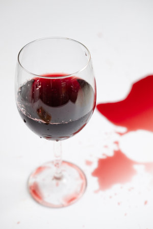 red wine in a transparent glass and spilled drink on a white backgroundの写真素材