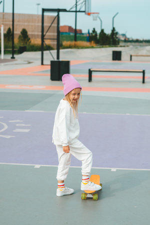 little blonde girl rides a skateboard. Unsafe skateboarding without protection