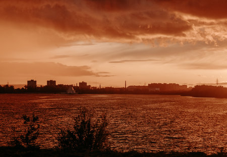 silhouette of the city at sunset near the river, against a red-orange backgroundの写真素材